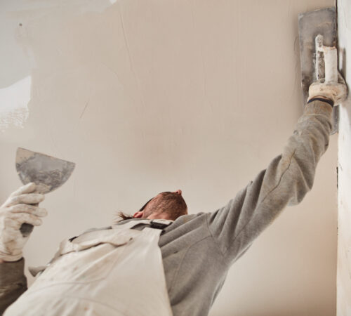 Worksman plastering gypsum walls inside the house.
